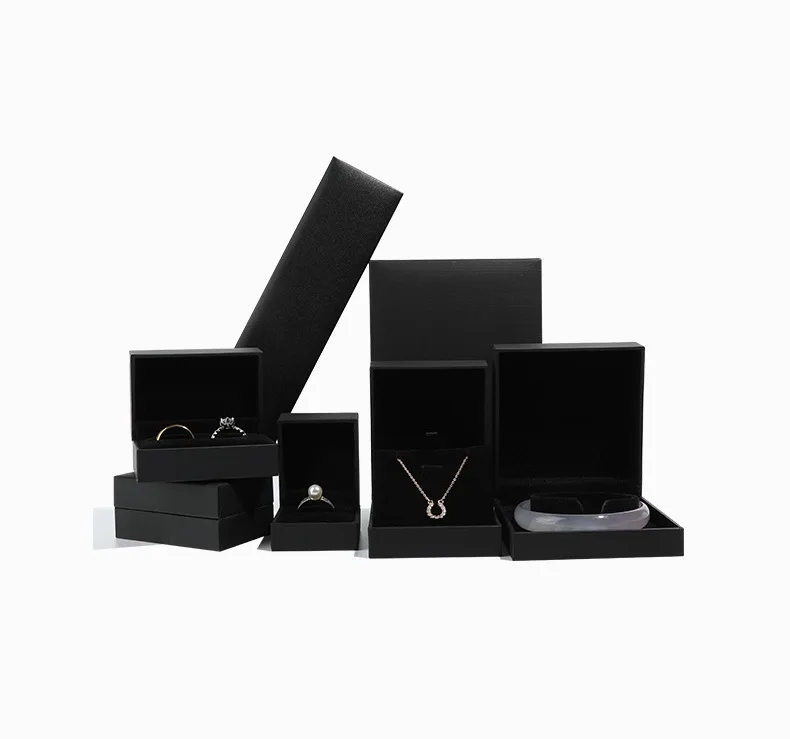 Open all-black rigid jewelry box displaying diamond ring contrast.