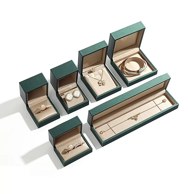 Open green jewelry box displaying gold satin lining for rings.