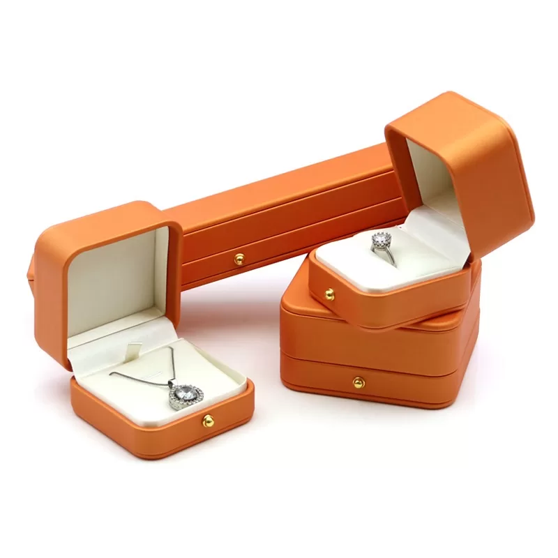 Close up of gold press stud on vibrant orange leatherette box.